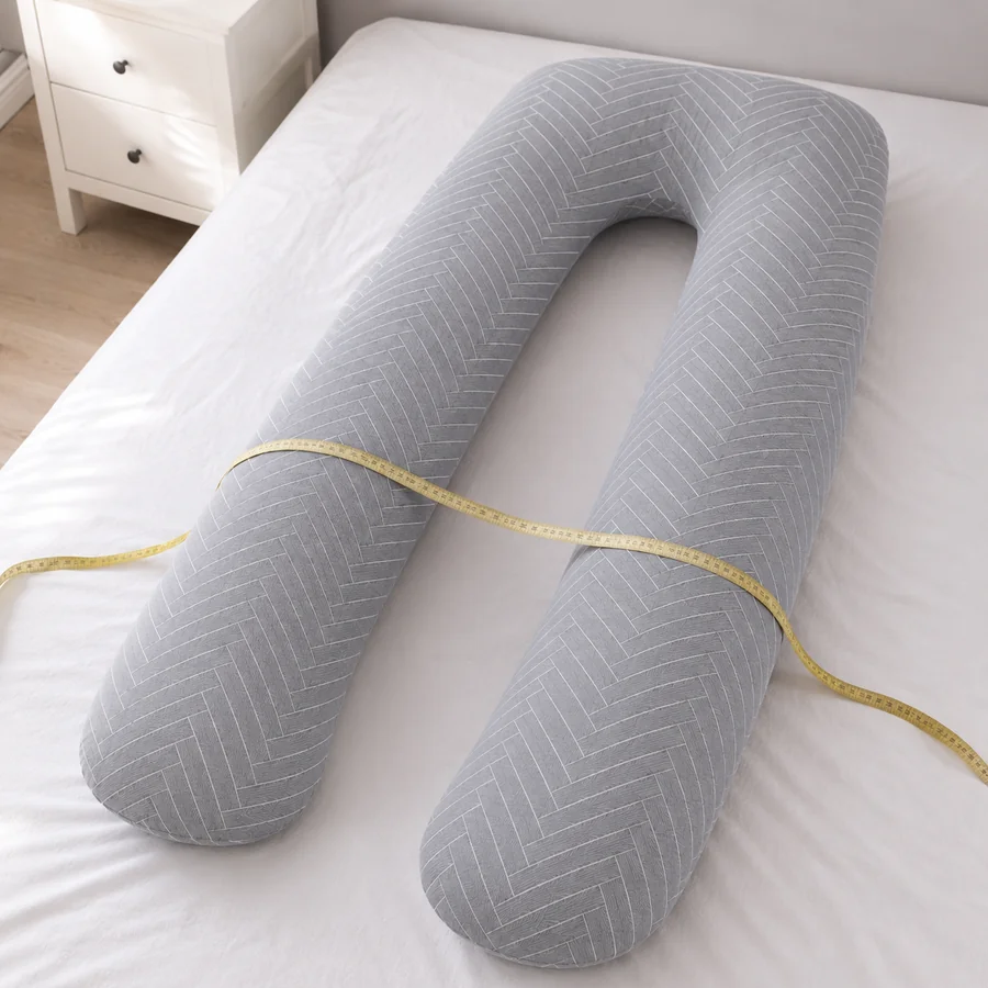Maßband quer über dem U-förmigen Stillkissen auf einem Bett